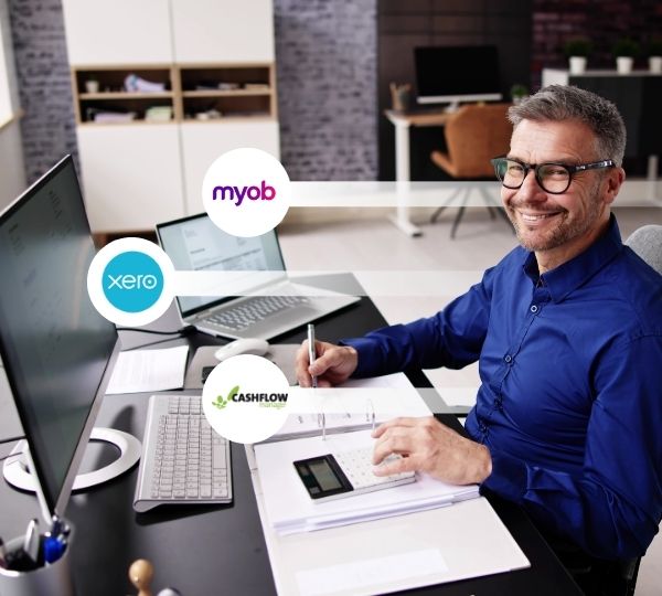A tax agent seated at a desk surrounded by financial documents, using a computer and calculator with MYOB, Xero, and Cashflow logos visible, highlighting professional bookkeeping services in Australia.